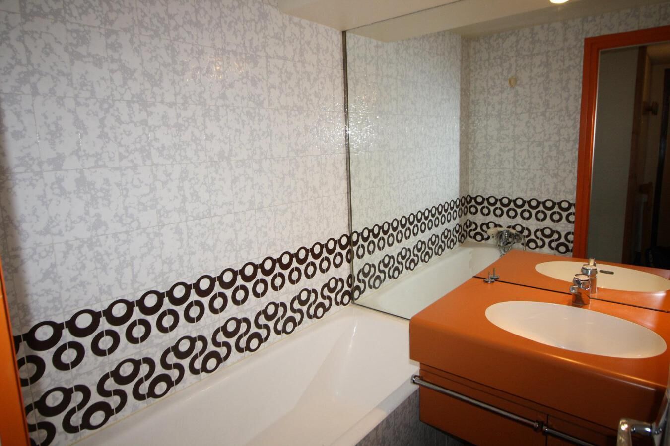 A bathroom with a bathtub, two sinks, and a mirror.