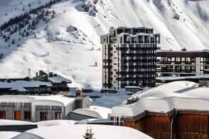 A snow-covered mountain town with modern buildings, including a multi-story hotel with balconies.