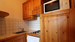 A kitchen with wooden cabinets, a microwave, a sink, and a dishwasher. - 10m from ski slopes, 2nd floor, balcony, 33m², Méribel-Mottaret (Méribel - Les Allues)