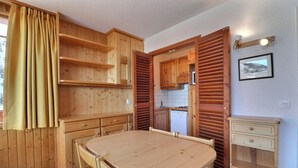 A wooden interior with a dining table, cabinets, and a kitchen area. - 10m from ski slopes, 2nd floor, balcony, 33m², Méribel-Mottaret (Méribel - Les Allues)
