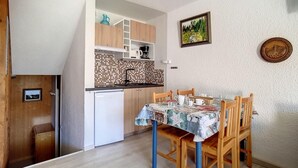 Uma cozinha compacta com painel de azulejos, armários de madeira e uma mesa de jantar com cadeiras.
