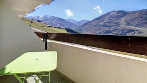 Uma varanda com vista para montanhas e uma mesa verde.