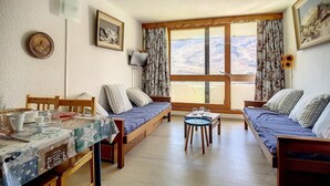 Quarto aconchegante com cama de madeira, uma pequena mesa de jantar e uma janela com cortinas.
