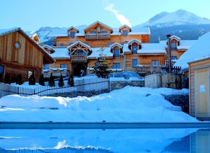 A wooden lodge with multiple balconies and a snow-covered landscape. - Wifi, swimming pool, parking, tv, 20m², Les Orres (Les Orres)