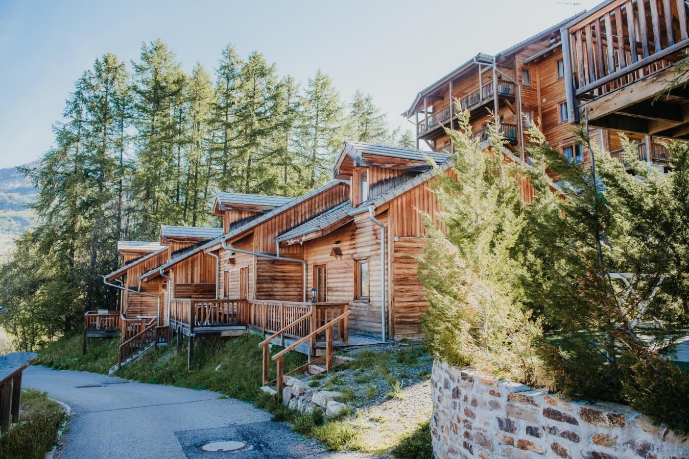 Eine hölzerne Hütte mit mehreren Ebenen, Außenstufen und einer Steinmauer.