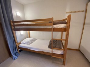 A bunk bed with a wooden frame, a mattress, and a pillow.