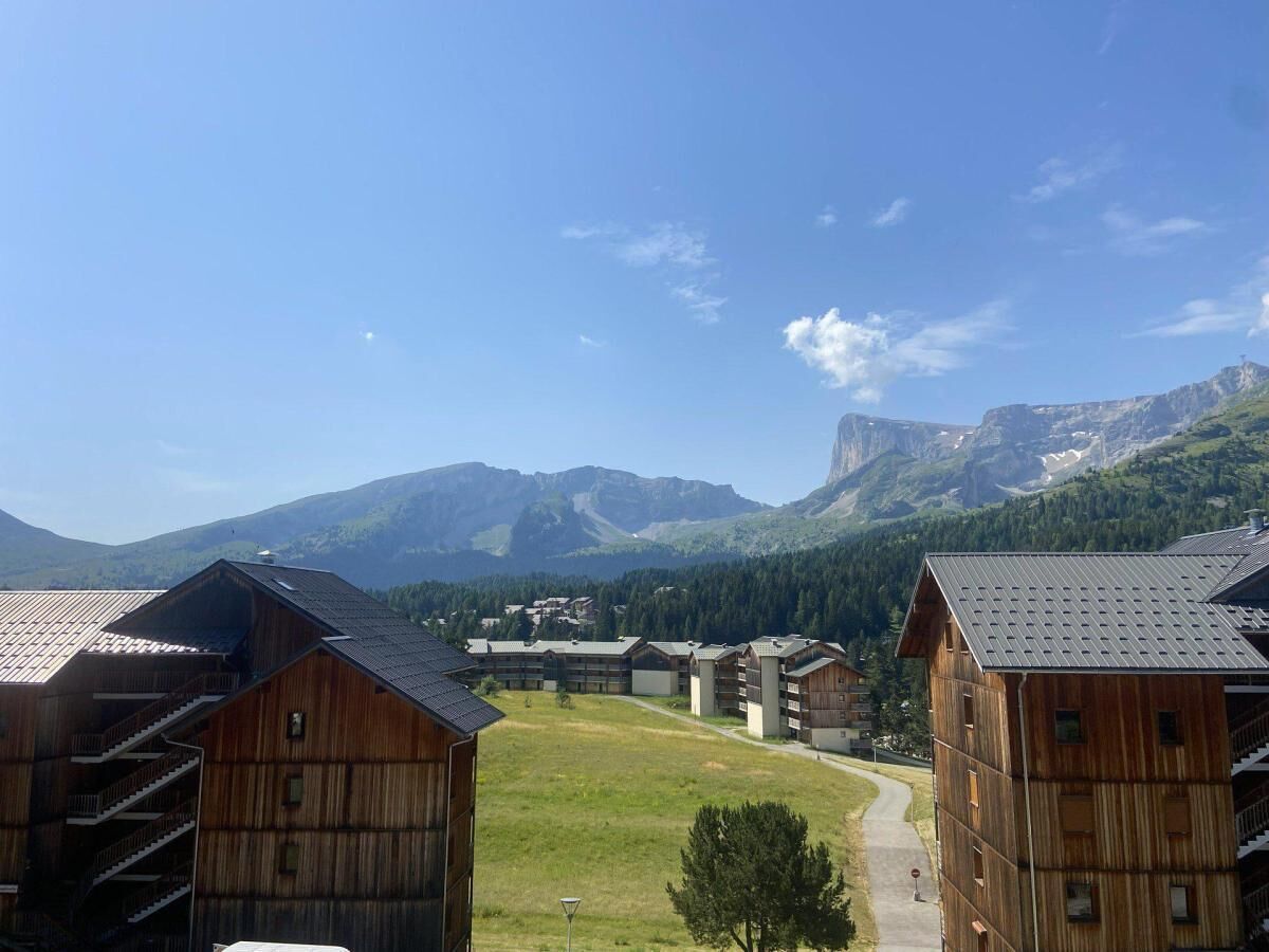 A mountain resort with wooden buildings, a clear sky, and a view of distant mountains.