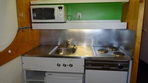 Una kitchenette compacta equipada con microondas, pileta, estufa y lavavajillas.