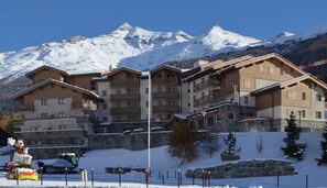 Um hotel com vários andares, acesso direto ao teleférico e montanhas ao fundo.