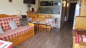 A cozy living room with a plaid sofa, wooden chairs, a small table, and a kitchenette in the background. - 100m from ski slopes, 2nd floor, view valley, balcony, tv, 30m², Les Arcs (Les Arcs)