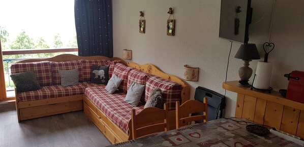 A cozy room with a wooden sofa, a small table, and a TV.
