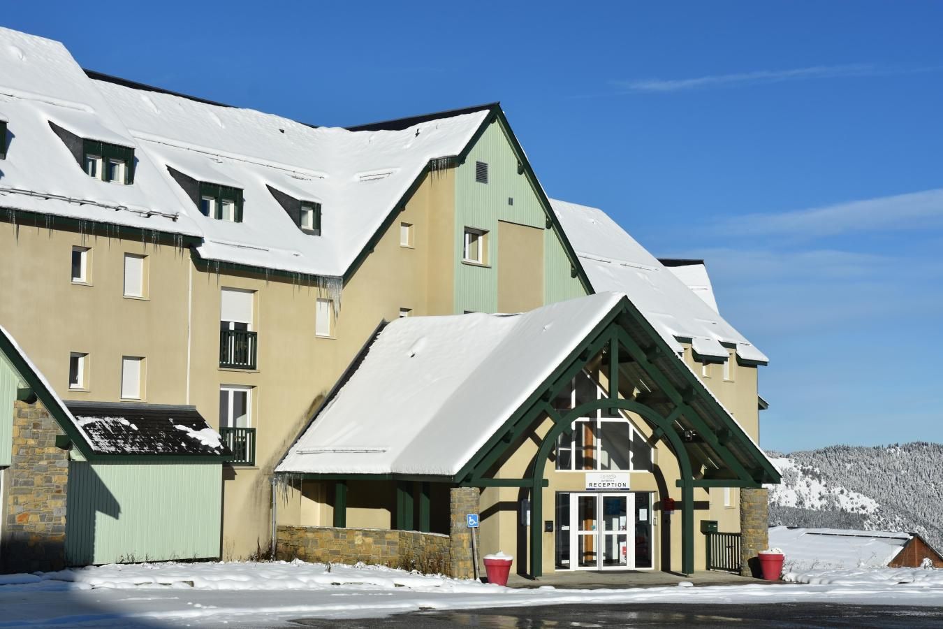 A hotel with a reception area, multiple windows, and a snow-covered roof.