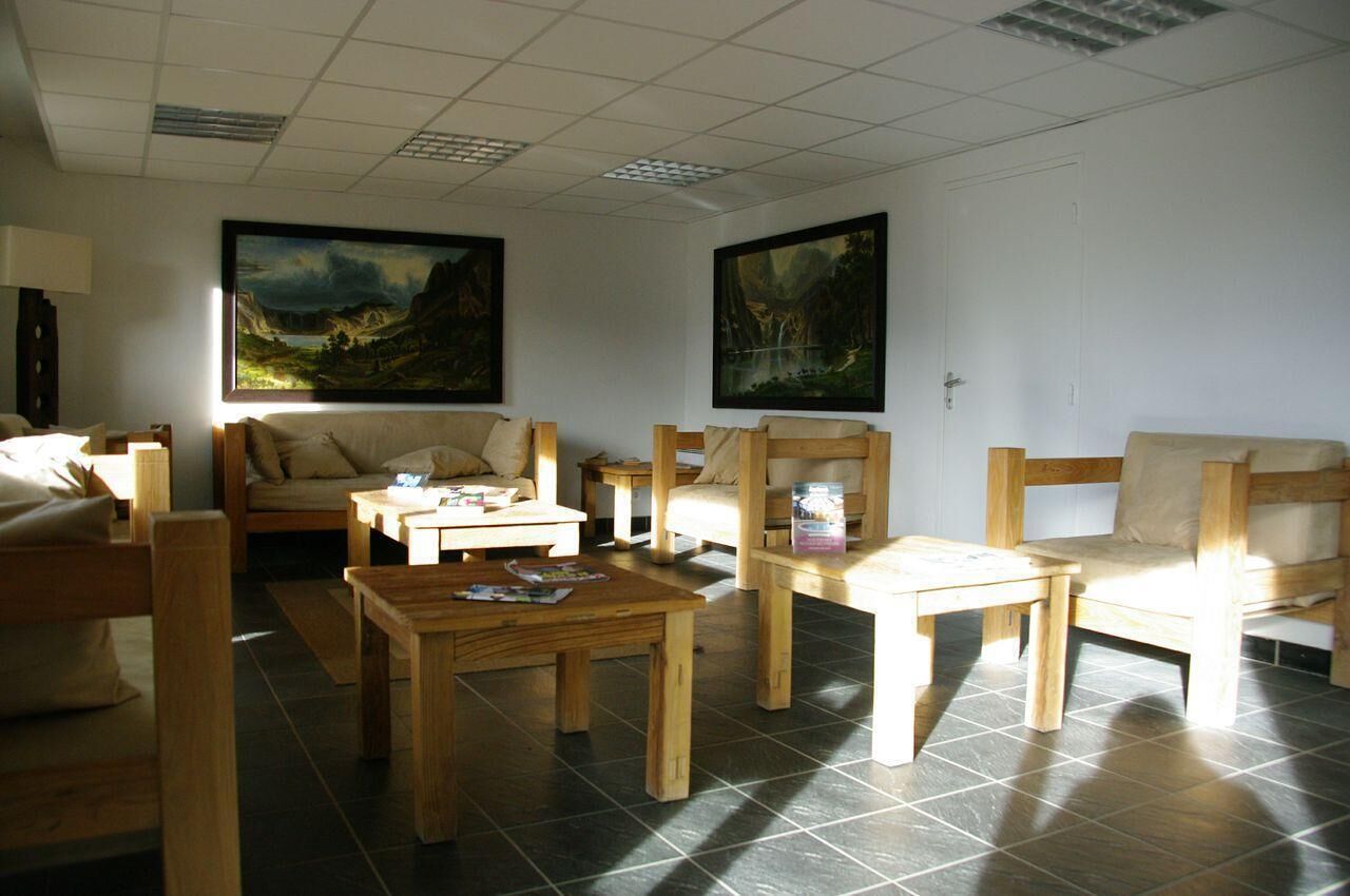 A cozy living room with wooden furniture, a sofa, a coffee table, and two paintings on the wall.