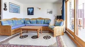 A cozy living room with a wooden sectional sofa, a small wooden table, and a large window with curtains. - 150m from ski slopes, 1st floor, terrace, tv, 75m², Peisey-Vallandry (Landry)