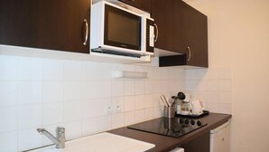 Eine kleine Küche mit Mikrowelle, Herd, Spüle und Kaffeemaschine.