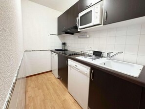 A compact kitchen with a microwave, stove, sink, and dishwasher.