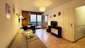 A cozy living room with a sofa, a television, and a dining area with a table and chairs. - Ski-in/ski-out & foot of the slopes, 2nd floor, view swimming pool, swimming pool, sauna, hammam (Les Orres)