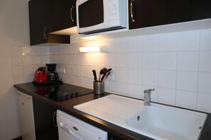 Une cuisine compacte équipée d’un four à micro-ondes, d’une cuisinière, d’une machine à café et d’un évier.