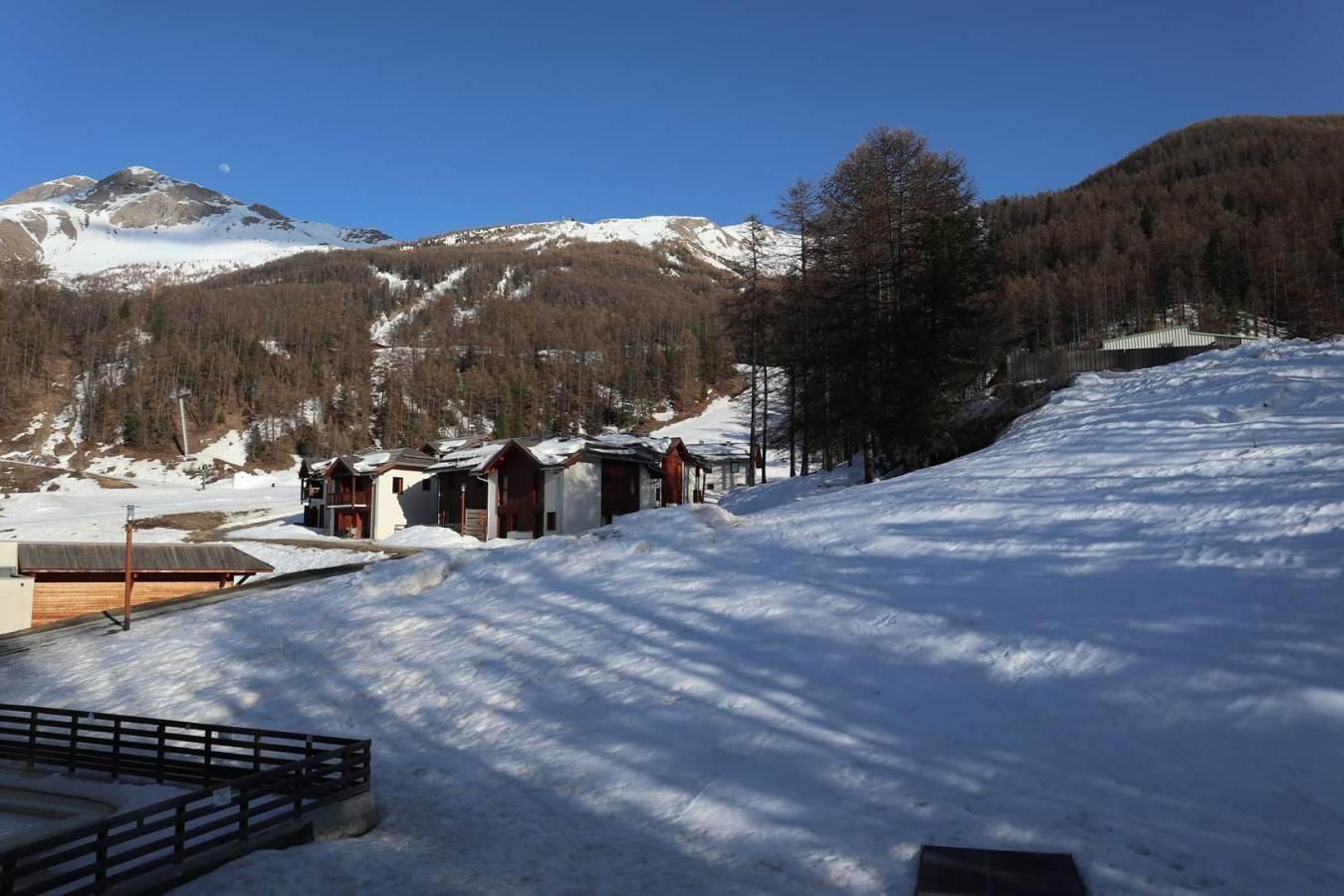 Un paysage montagneux enneigé, avec une rangée de chalets.