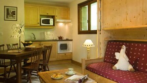 Una cucina accogliente con mobili in legno, un forno a microonde, un forno e un'area pranzo con tavolo e sedie.