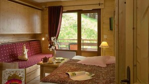 Una camera in stile baita con un letto, un divano, un tavolo con una lampada e una finestra con tende.