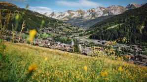 Un borgo montano con edifici tradizionali, una chiesa e una valle.