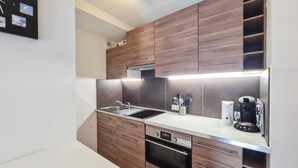 A compact kitchen with wooden cabinets, a stainless steel sink, and a built-in dishwasher. - 100m from shops, 2nd floor, view mountain, tv, 30m², Flaine (Flaine)