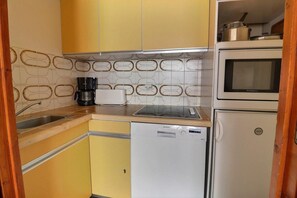 A compact kitchen with a Siemens dishwasher, a microwave, and a coffee maker.