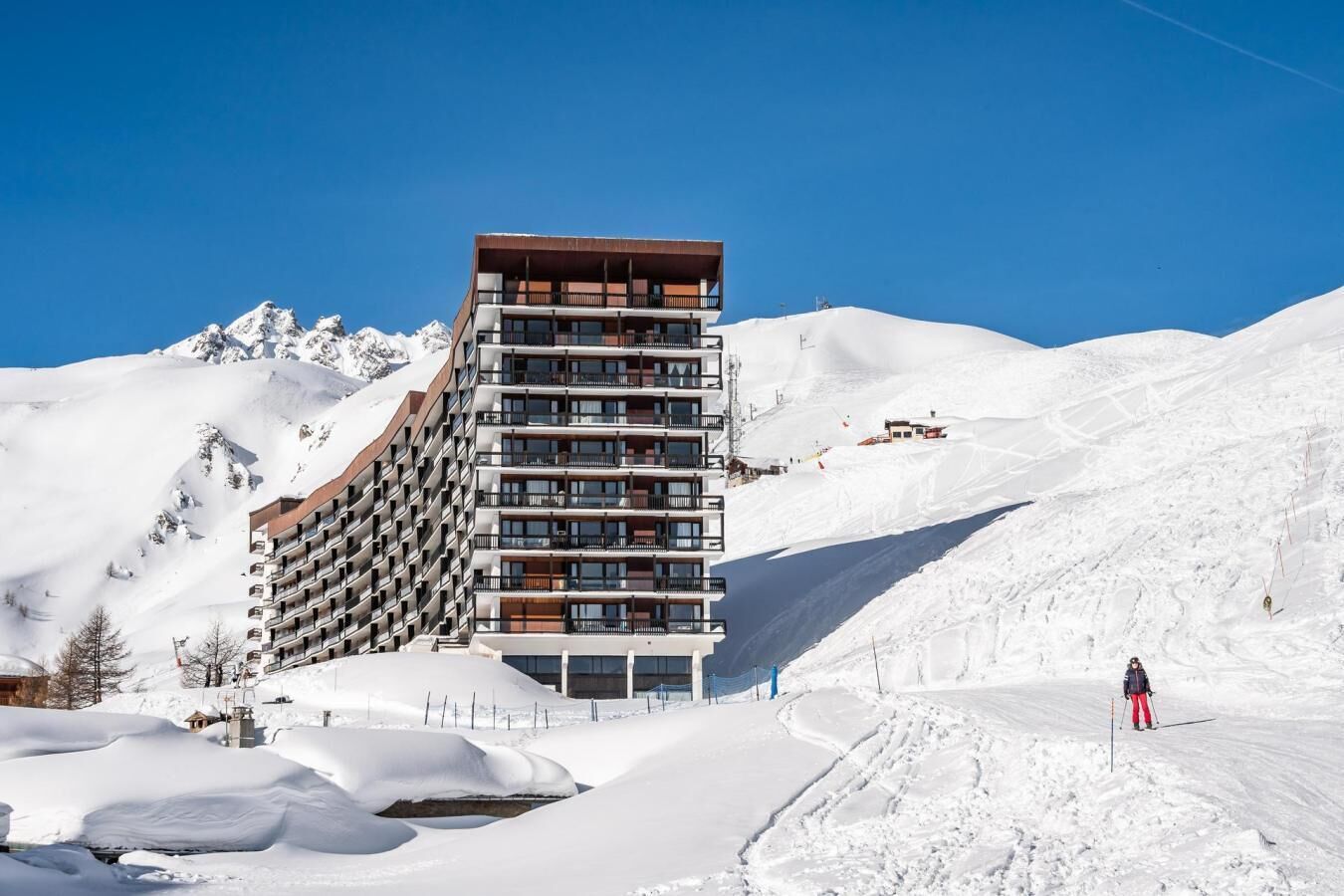 A multi-story hotel with balconies, situated in a snowy mountainous area.