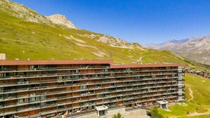 Ein mehrstöckiges Hotel mit Balkonen vor einer Bergkulisse.