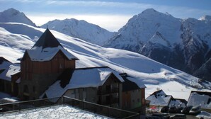 A snow-covered mountain with a wooden building featuring a steep roof and a stone archway.