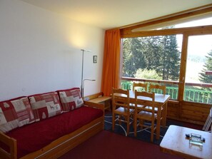 A cozy room with a wooden sofa, a small table, and a window with curtains.
