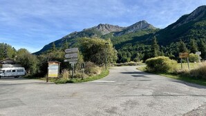 A road leading to a mountainous area with a sign indicating directions to various locations. - 300m from resort center, 1st floor, balcony, tv, 33m², Serre Chevalier (Le Monêtier-les-Bains)