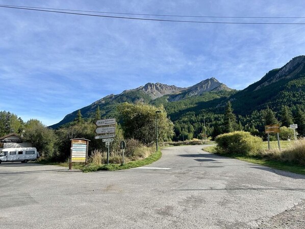 A road leading to a mountainous area with a sign indicating directions to various locations.