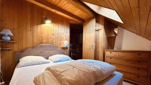 A wooden cabin bedroom with a bed, bedside lamp, and a dresser. - 300m from resort center, 1st floor, balcony, tv, 33m², Serre Chevalier (Le Monêtier-les-Bains)
