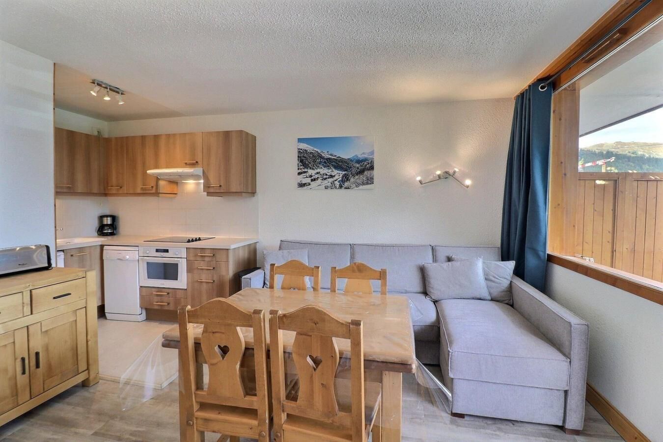 Een compacte keuken met houten kastjes, een eettafel met stoelen en een bank.