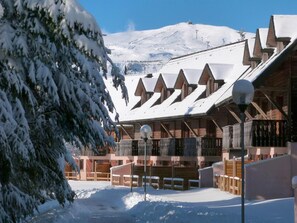 A snow-covered lodge with wooden cabins and a mountain backdrop.