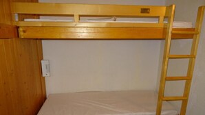 Una cama litera con escalera, un enchufe y una alfombra azul con lunares.