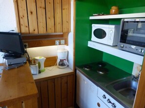 A compact kitchen with wooden cabinets, a microwave, a stove, and a coffee maker. - 50m from ski slopes, 5th floor, tv, 35m², Les Arcs (Les Arcs)