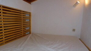 Een kamer met een bed, een houten lattenpannen hoofdbord, een wandlamp en een stopcontact.