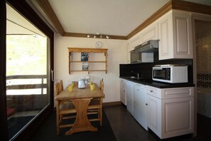 A compact kitchen with a dining table, white cabinets, a microwave, and a coffee maker.