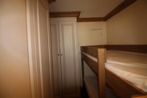 A narrow room with a bunk bed and a wardrobe.