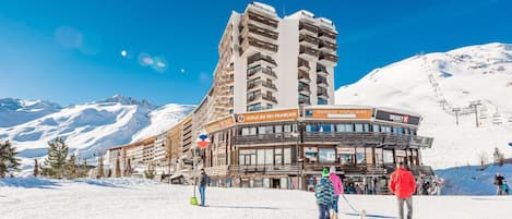 Un edificio de estación de esquí con varios balcones y señalización que indica 'Ecole du Ski Francais' y 'Banque Populaire'.