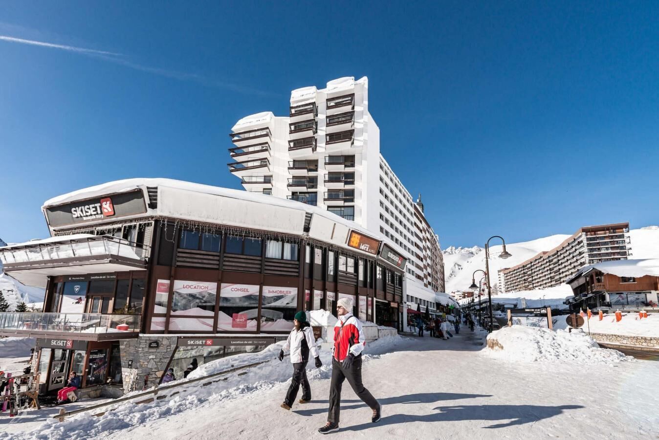 A ski resort building with multiple floors, a ski lift, and a snowy landscape.