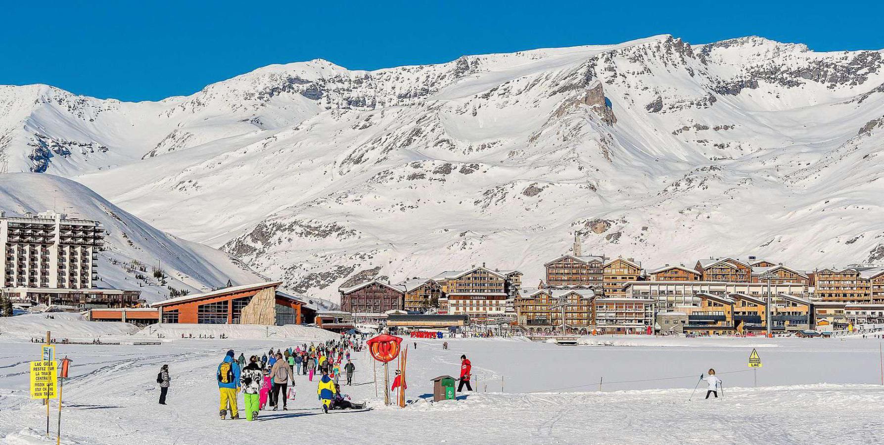 A snow-covered mountain with a ski resort in the foreground, featuring buildings with balconies and a ski lift.