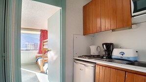 A compact kitchen with wooden cabinets, a white refrigerator, a coffee maker, and a toaster. - Ski-in/ski-out & foot of the slopes, 1st floor, balcony, tv, 22m², Les Menuires (Les Menuires)