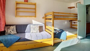 A bunk bed with a wooden frame, a sofa with patterned cushions, and a small shelf with a vase. - Ski-in/ski-out & foot of the slopes, 1st floor, balcony, tv, 22m², Les Menuires (Les Menuires)