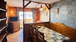 Una habitación acogedora con una mesa y sillas de madera, un muro de piedra y una ventana con cortinas.