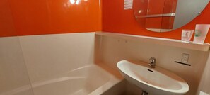 A bathroom with a white bathtub, a sink, and a mirror.