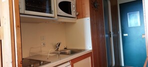 A compact kitchen with a sink, a microwave, and a stove.